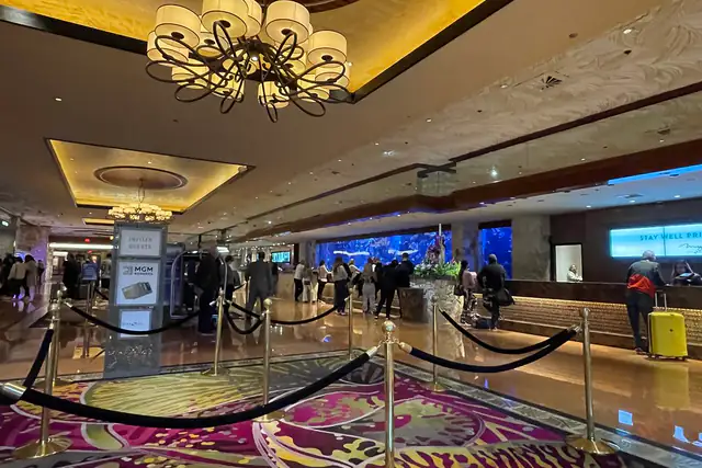 Resort casino lobby with chandeliers, patterned carpet and gaming floor beyond
