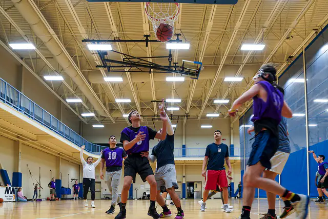 Players going for a rebound during an indoor basketball game