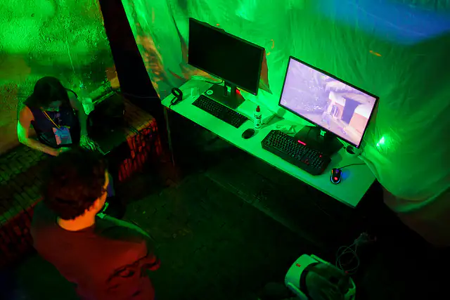 Gamers playing at PC stations lit with green light at a gaming event