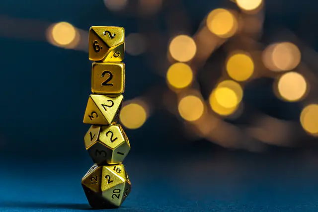 A stack of gold polyhedral dice against warm bokeh lights