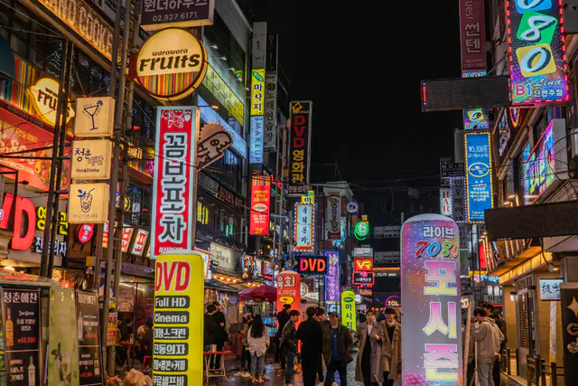 Crowded Asian city street at night lined with neon shop signs