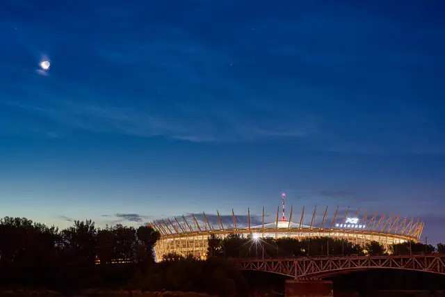 Floodlit stadium glowing under a deep blue evening sky